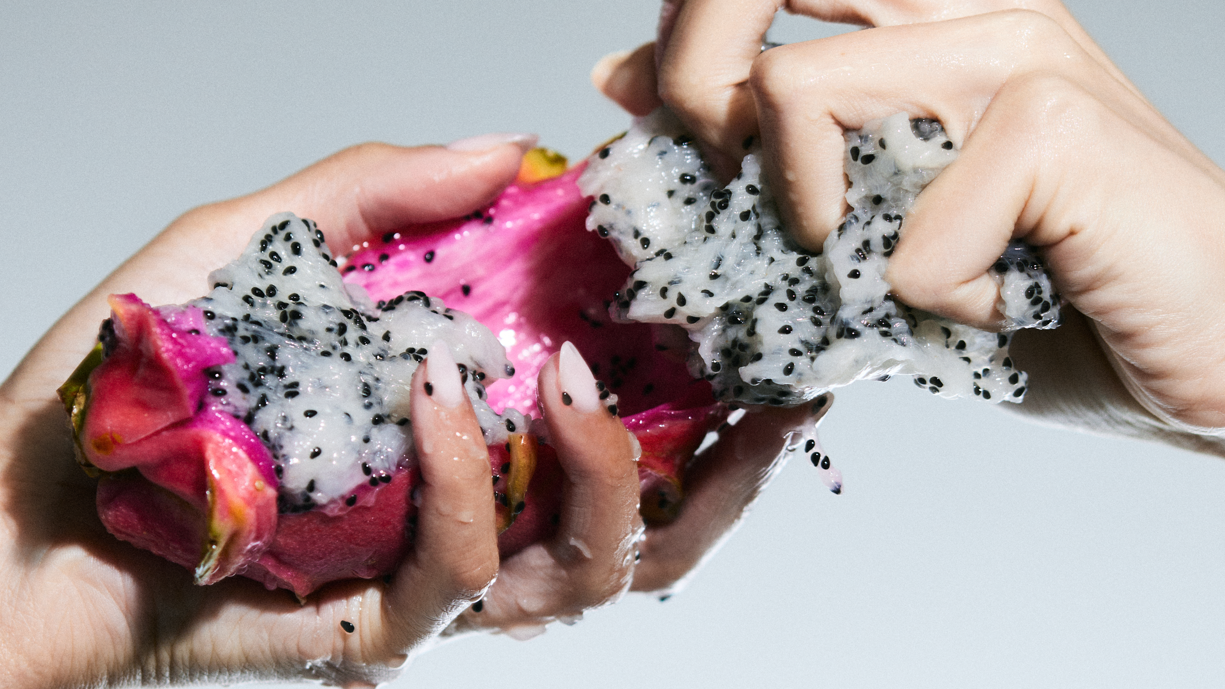 Two hands pulling apart a dragon fruit