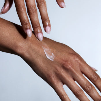 A picture of a person's hands, with one applying Habelo Anti-Aging Activating Hand Serum to the other